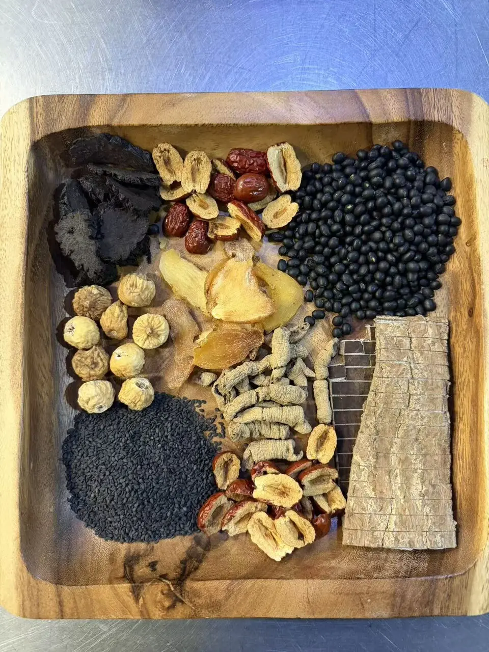 The ingredients for Julia's Kitchen's five-black lower-back soup (五黑壯腰湯), laid out on a wooden tray before simmering, black beans, black sesame, red dates and dried herbs