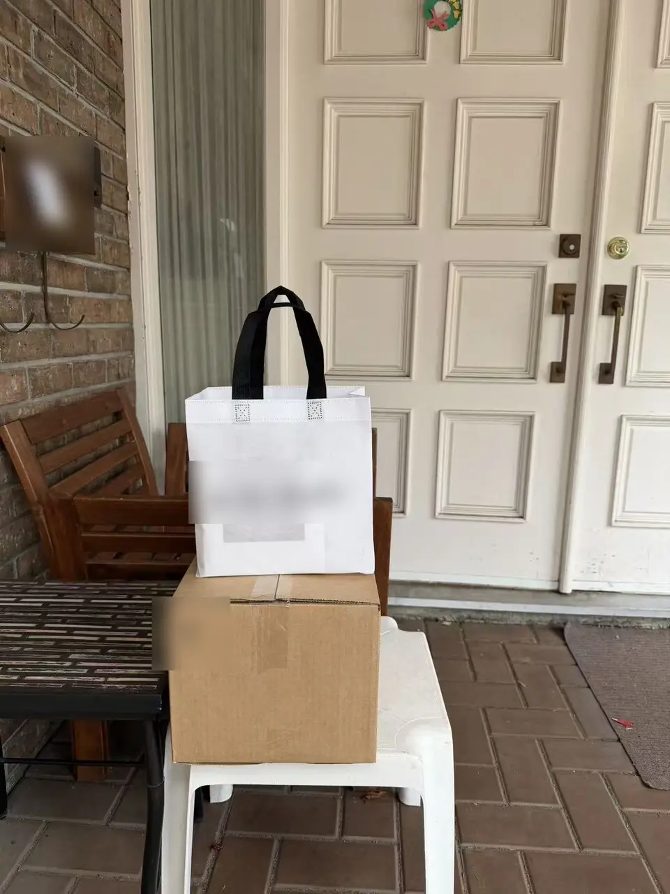 A confinement meal delivery box on a white stool on a client's porch, with a white tote bag on top