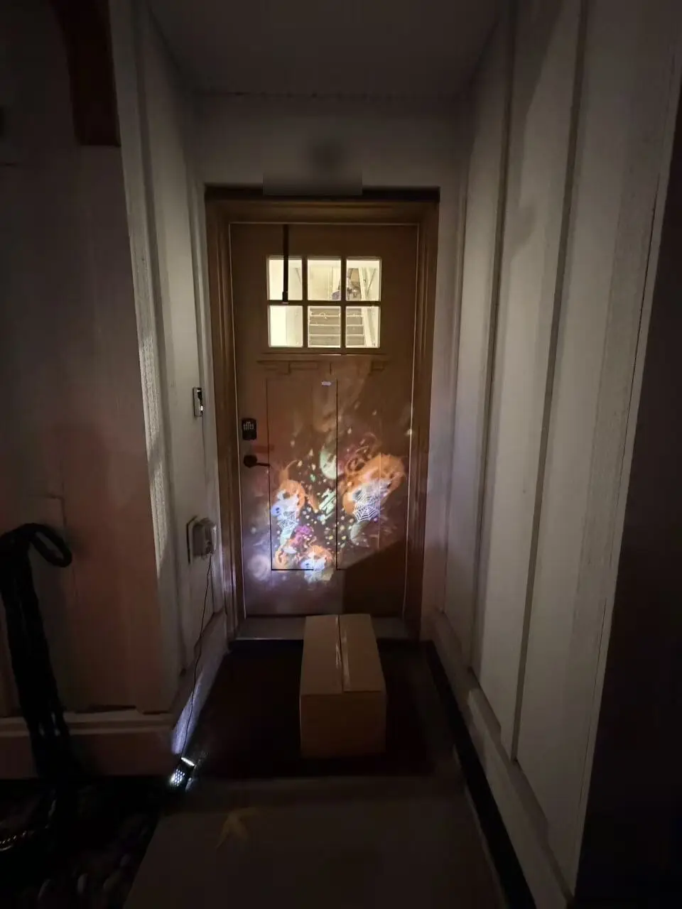 A confinement meal delivery box at a client's wooden front door at the end of a dim entryway